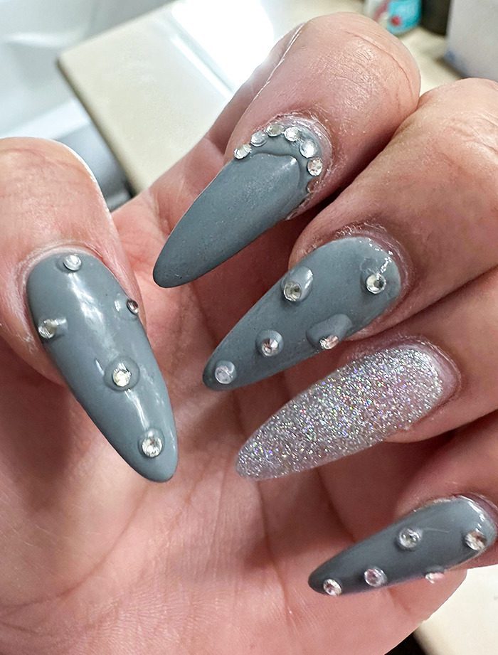 A hand with long nails with rhinestones Description automatically generated