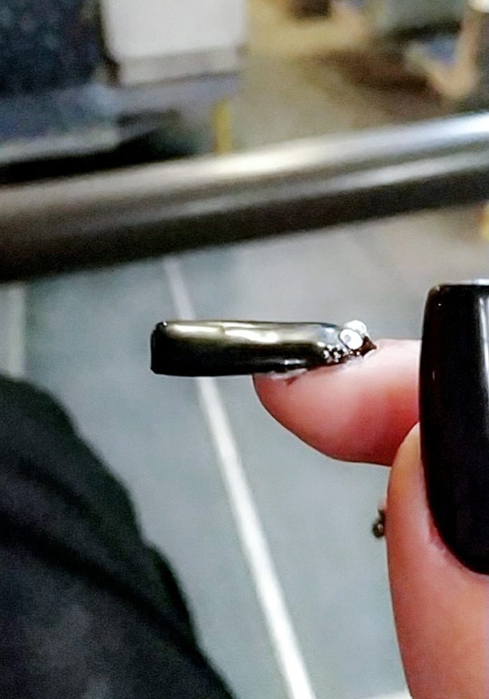 A person holding a black nail polish
Description automatically generated